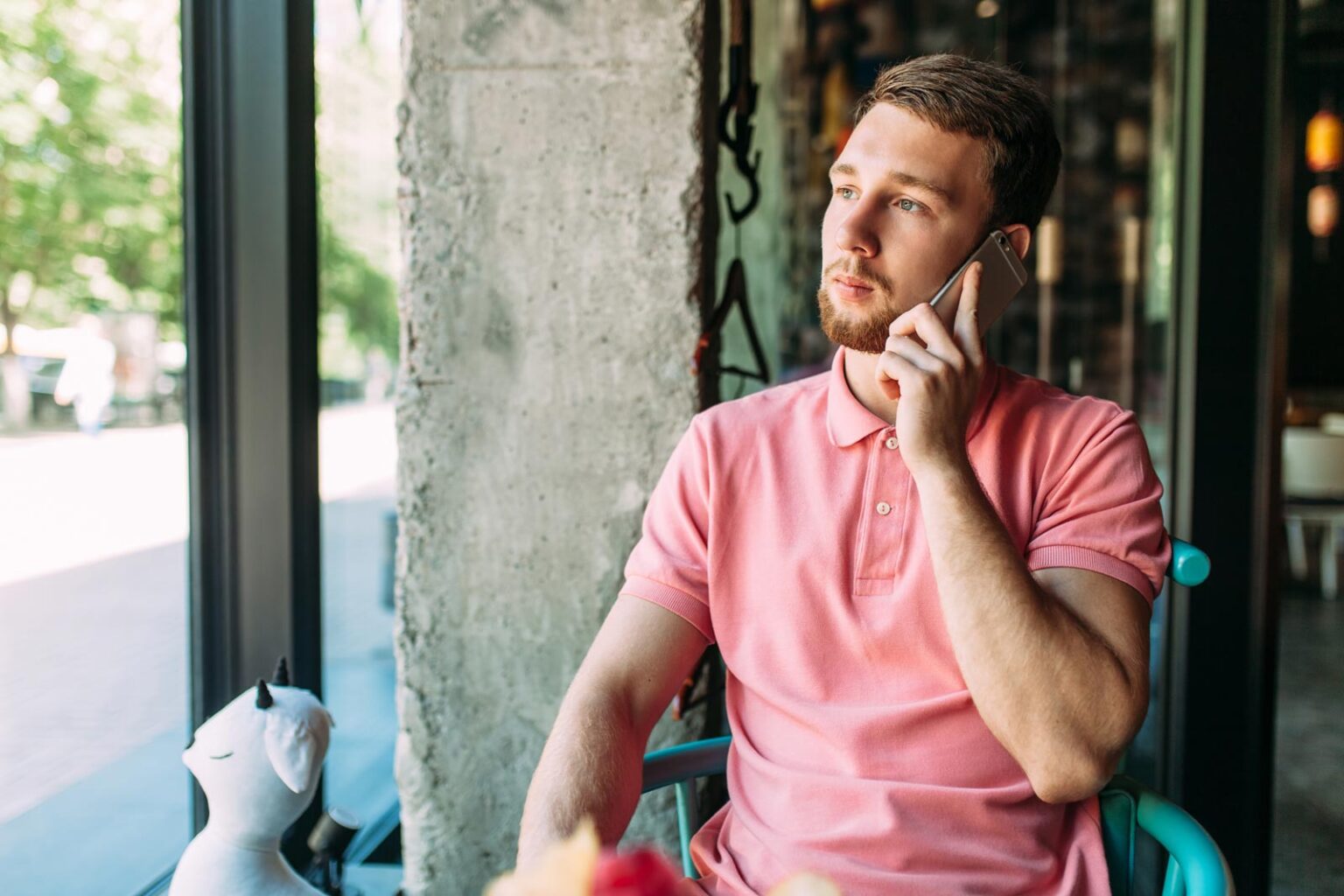 Young man sitting in a cafe and talking to a phone